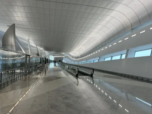 Nowoczesny, jasny korytarz lotniskowy z ruchomymi schodami w AUH Zayed International.
