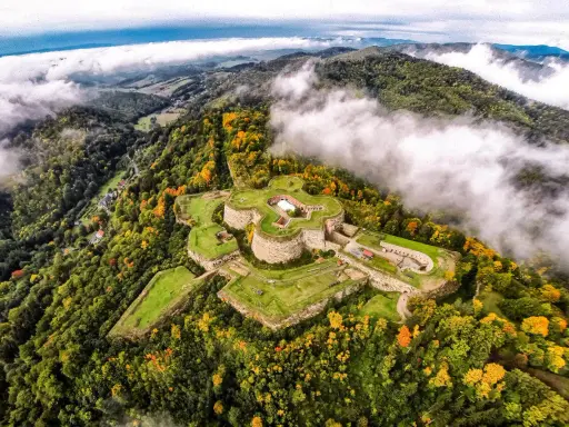 Twierdza na wzgórzu, otoczona jesiennym lasem. Idealne miejsce, gdzie na weekend poczuć historię i podziwiać widoki.