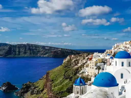Santorini wakacje: białe domy z niebieskimi kopułami na klifie nad lazurowym morzem. Widok zapiera dech w piersiach.
