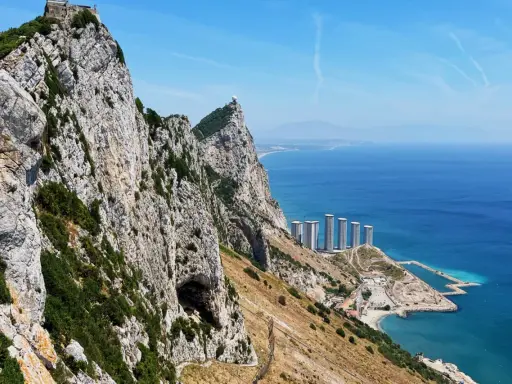 Gibraltar, brytyjskie terytorium na półwyspie iberyjskim, z górującą skałą, jaskinią i nowoczesnymi budynkami nad błękitnym morzem.
