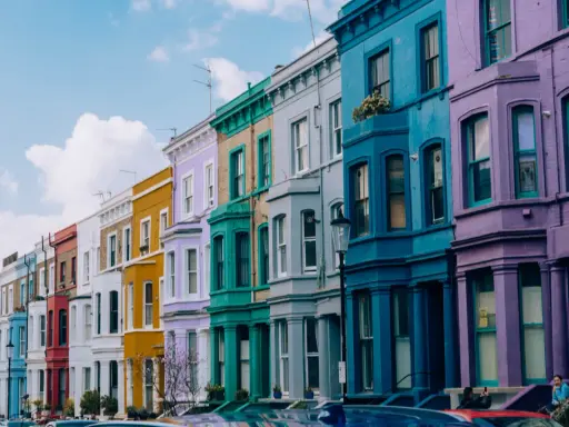 Kolorowe kamienice w Notting Hill w Londynie, tworzące tęczowy rząd pod błękitnym niebem.