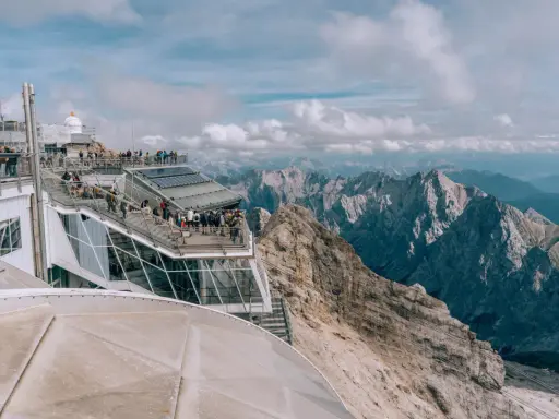 Tłum turystów na tarasie widokowym najwyższego szczytu Niemiec, Zugspitze, podziwia alpejskie krajobrazy.