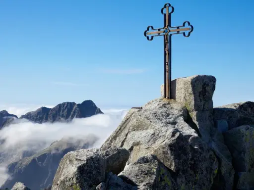 Krzyż na skalistym szczycie, najwyższy szczyt Karpat, góruje nad morzem chmur.