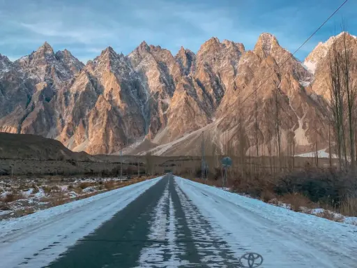Droga przez ośnieżoną dolinę w kierunku majestatycznych gór Hunza.