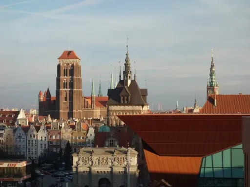 Gdańsk stare miasto z Bazyliką Mariacką i Ratuszem. Słońce oświetla zabytkowe kamienice i nowoczesną architekturę.