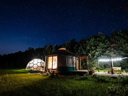 Nocne niebo nad jurta i kopułą. Idealne romantyczne miejsca w Polsce na wspólne chwile pod gwiazdami.