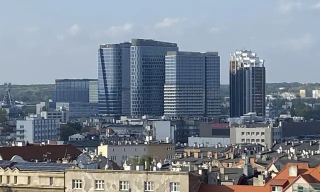 Nowoczesne wieżowce górują nad dachem kamienicy w największym mieście w Polsce.