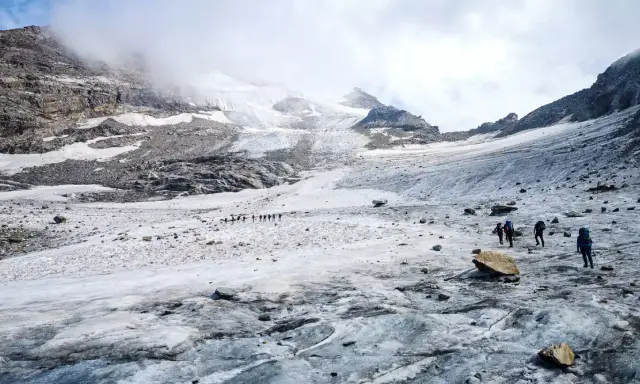 Grupa turystów wędruje po lodowcu w kierunku majestatycznego masywu Monte Rosa.