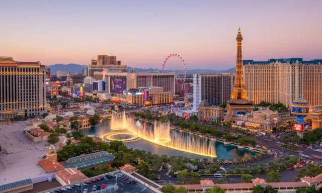 Las Vegas, miasto hazardu w USA, nocą. Widać fontanny, wieżę Eiffla i diabelski młyn.