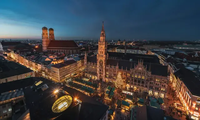 Nocny jarmark bożonarodzeniowy w Monachium. Rynek z oświetlonymi straganami i choinką, w tle Frauenkirche i Nowy Ratusz.