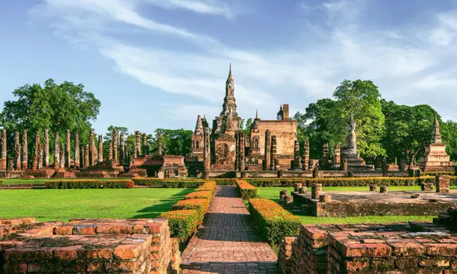Ruiny świątyń w historycznym parku Sukhothai, wpisanym na listę 7 cudów świata UNESCO, z posągiem Buddy i wieżami.