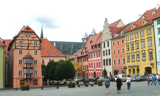 Kolorowe kamienice w **cheb** tworzą malowniczy rynek. Ludzie spacerują po brukowanym placu, podziwiając architekturę.