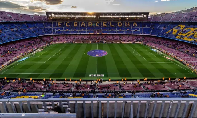 Widok na Camp Nou podczas zwiedzania. Piękny stadion FC Barcelona z murawą i trybunami wypełnionymi kibicami.