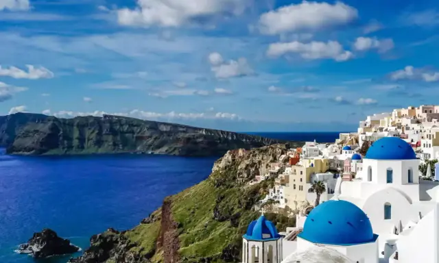 Santorini wakacje: białe domy z niebieskimi kopułami na klifie nad lazurowym morzem. Widok zapiera dech w piersiach.