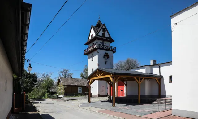 Wieża zegarowa i drewniany domek w słoneczny dzień.