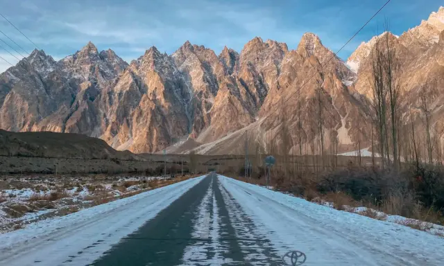 Droga przez ośnieżoną dolinę w kierunku majestatycznych gór Hunza.