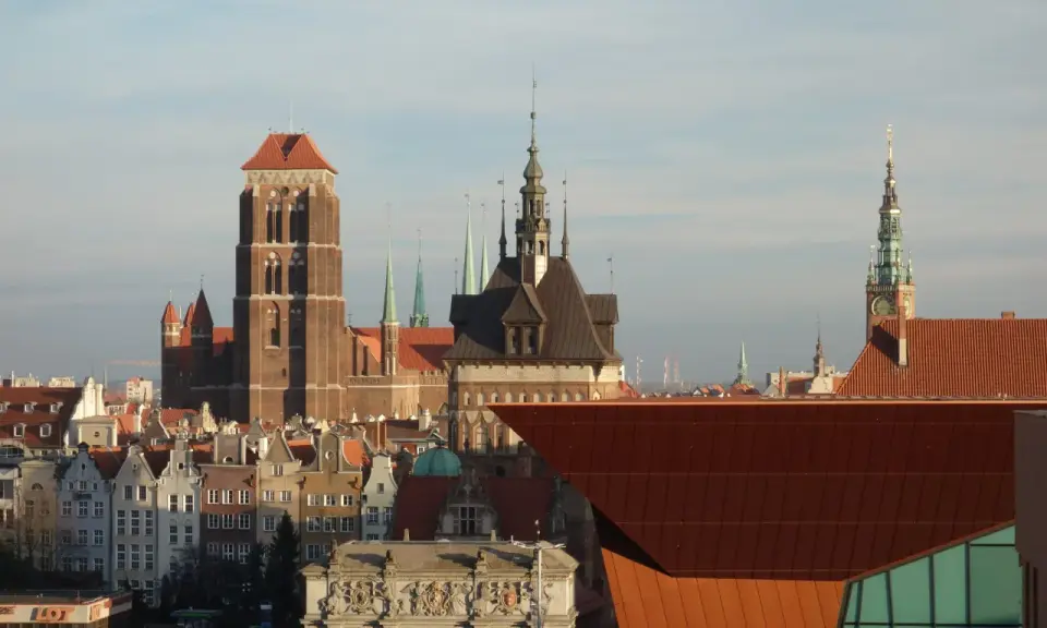 Gdańsk stare miasto z Bazyliką Mariacką i Ratuszem. Słońce oświetla zabytkowe kamienice i nowoczesną architekturę.