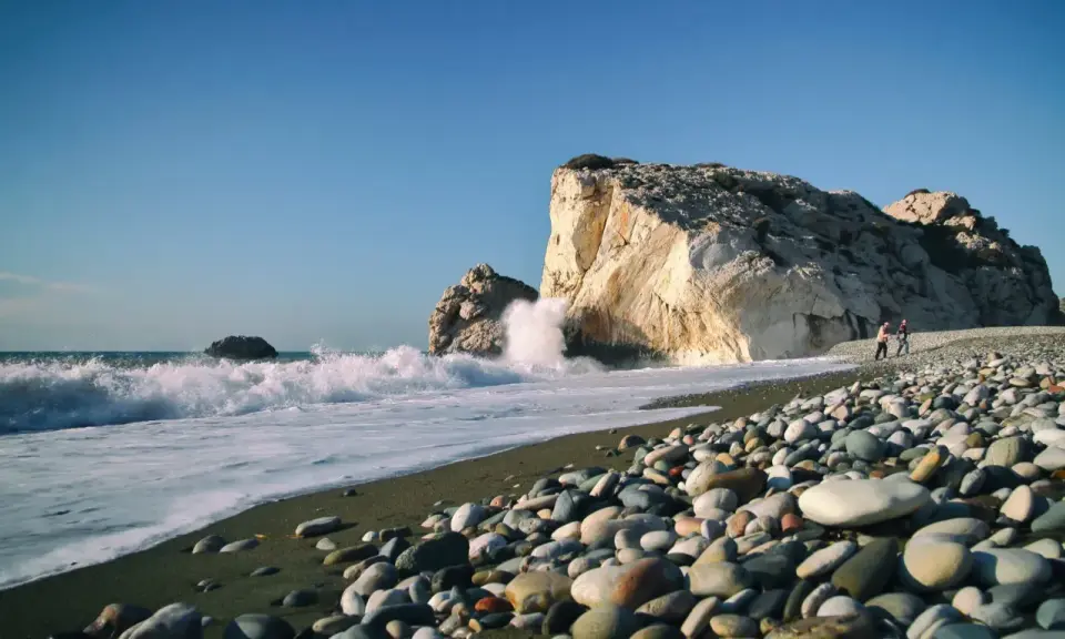 Kamienista plaża na wyspie Afrodyty, gdzie fale rozbijają się o skaliste klify.