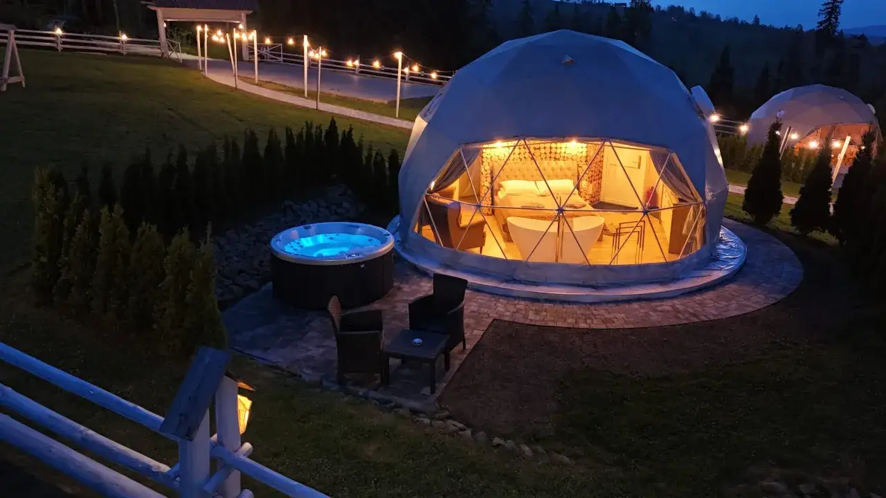 Glamping co to? Luksusowy namiot kopułowy z wanną i łóżkiem, obok jacuzzi, w otoczeniu górskiego krajobrazu.