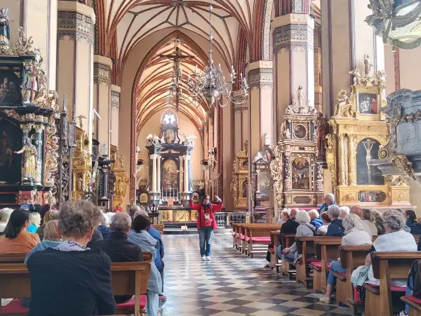 Wnętrze katedry we Fromborku, gdzie zwiedzający słuchają przewodniczki. Zamek Frombork zachwyca bogactwem zdobień.