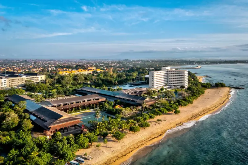Widok z lotu ptaka na wybrzeże Sanur z hotelami, basenami i plażą.